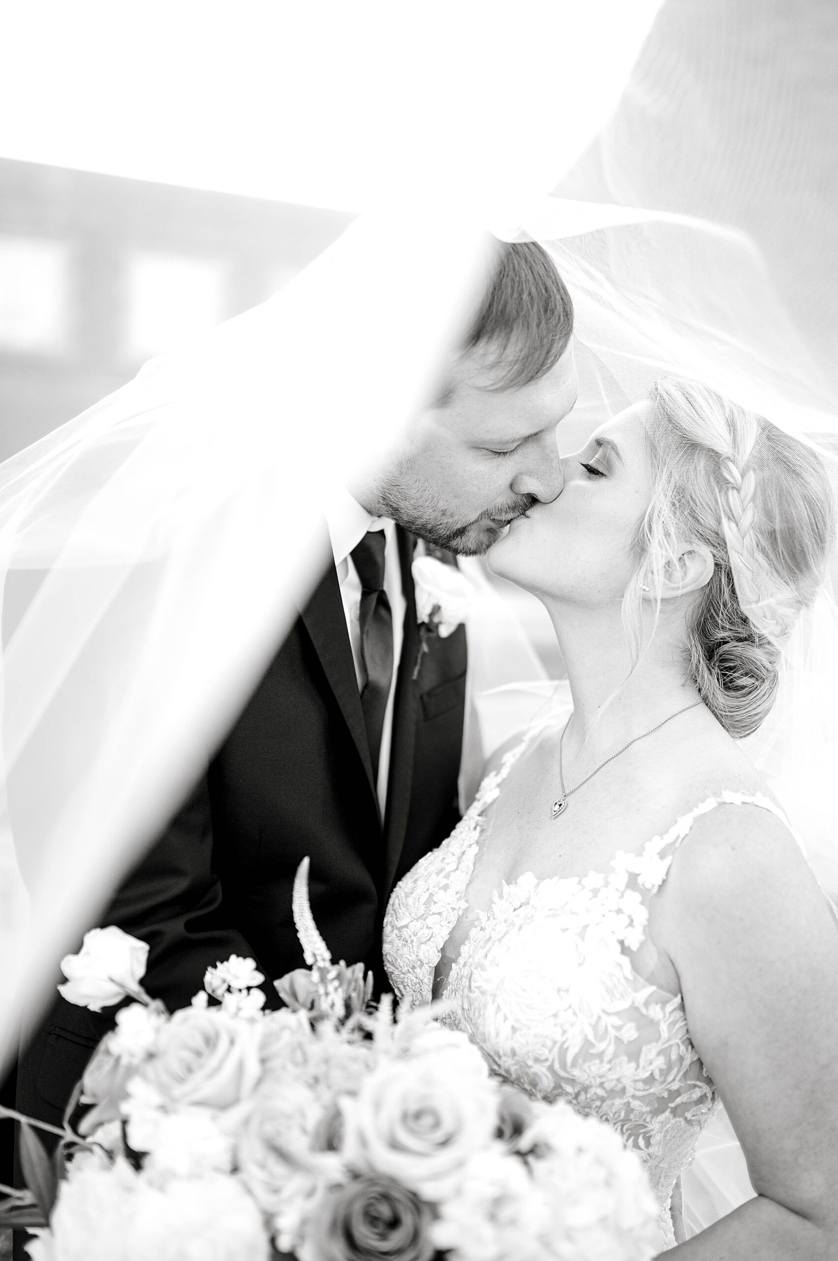 Bride and groom kissing under veil