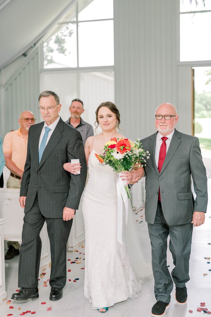 Bride walking down the aisle with dad and step dad