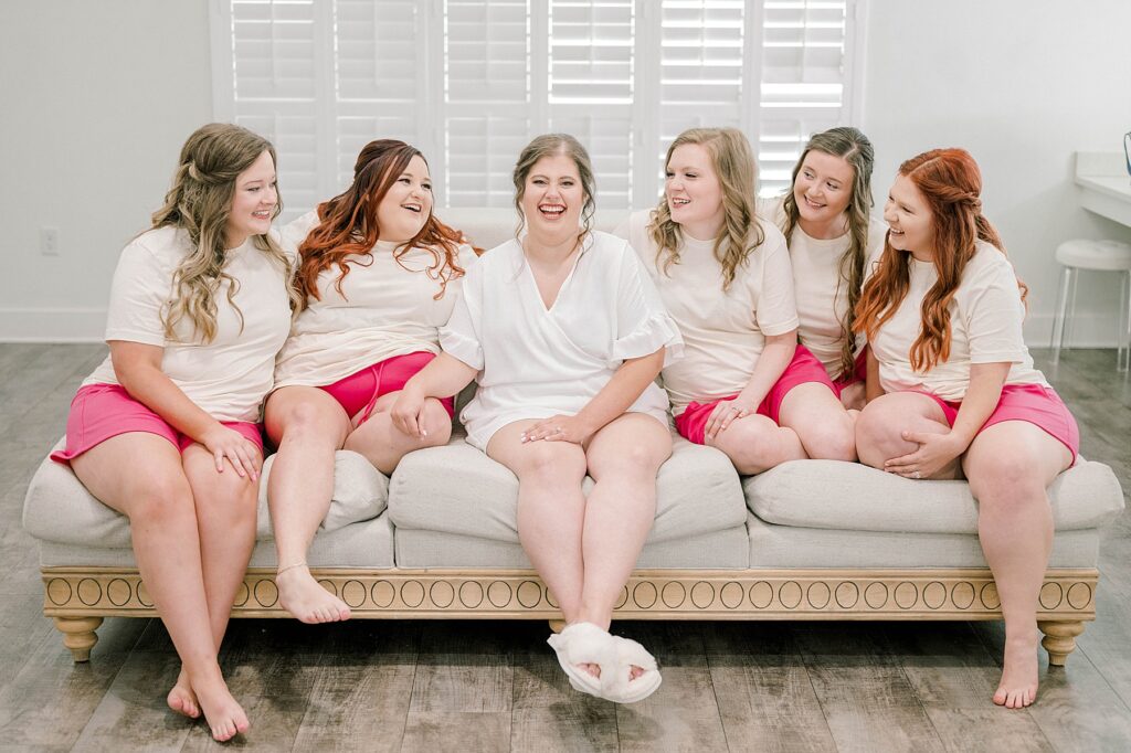 Bride and bridesmaids in matching PJ sets laughing on the couch