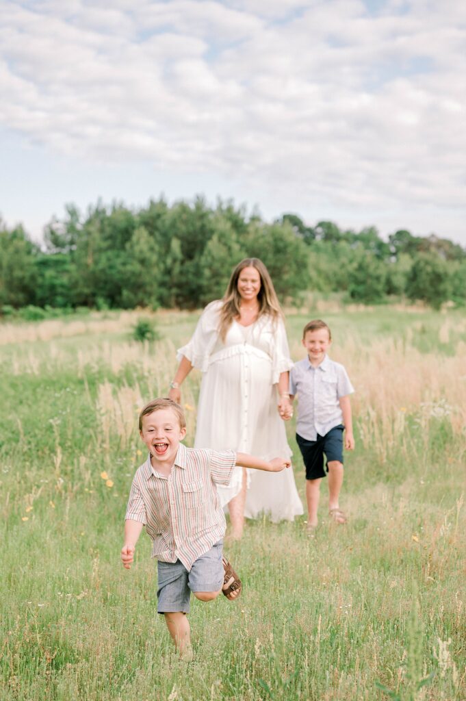 Boys running in field with mom